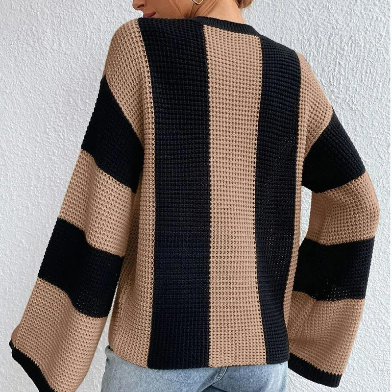 Person wearing a black and beige striped sweater against a white wall
