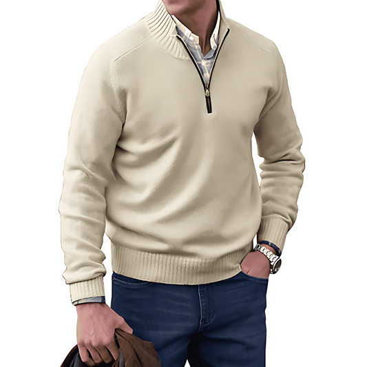 Man wearing a beige half-zip sweater and blue jeans on a white background