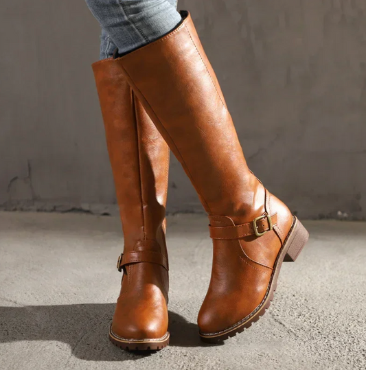 Brown knee-high boots with a buckle detail on a neutral background