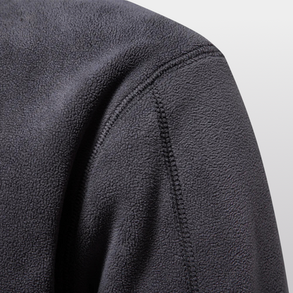 Close-up of a textured gray fleece fabric with stitching detail on a light gray background