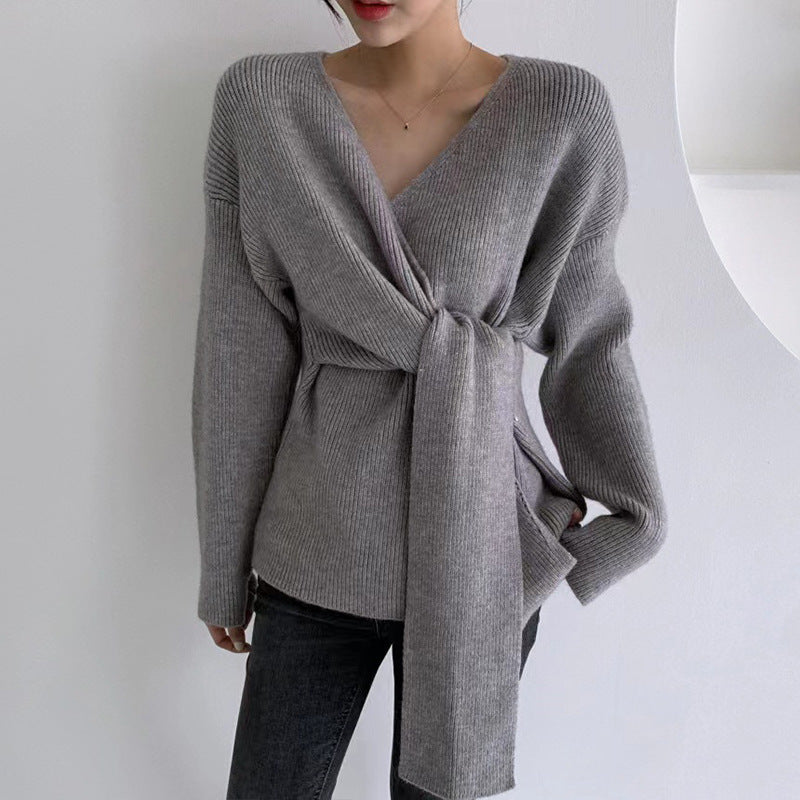 Gray wrap sweater worn by a person on a plain background
