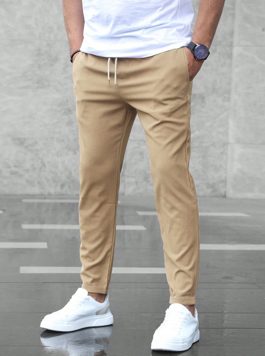 Person wearing beige pants and white sneakers on a gray floor.