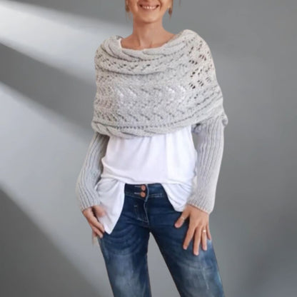 Woman wearing a large knitted shawl over her shoulders against a plain background