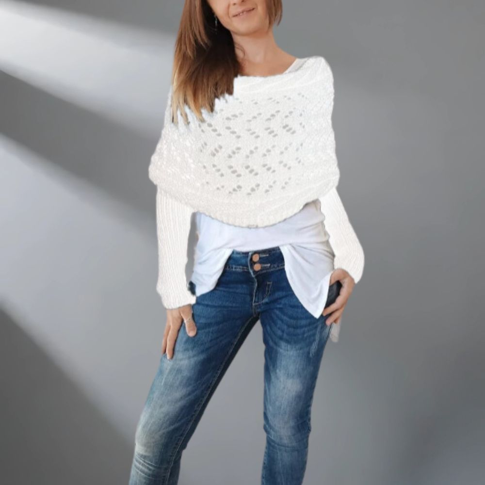 Woman wearing a white knitted sweater over a light blue shirt and blue jeans on a gray background