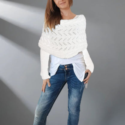 Woman wearing a white knitted sweater over a light blue shirt and blue jeans on a gray background