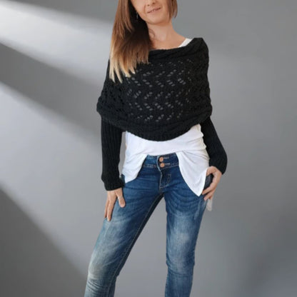 Woman wearing a black knitted shawl over a white top and blue jeans on a gray background