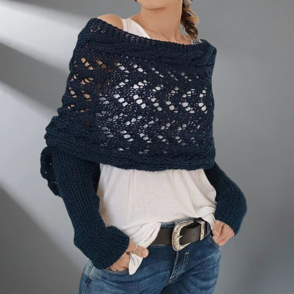 Person wearing a dark blue knitted shawl over a white top and jeans on a gray background