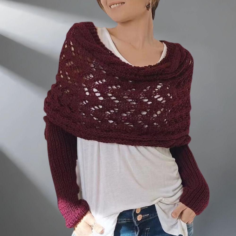 Person wearing a burgundy knitted shawl over a white shirt with a gray background