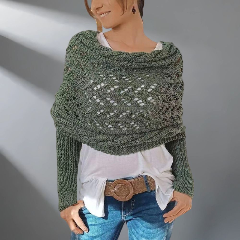Person wearing a green knitted shawl over a white shirt and blue jeans on a gray background