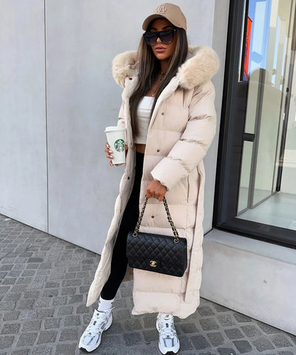 Woman in a long beige puffer coat with a fur hood, holding a Starbucks cup and a Chanel handbag.