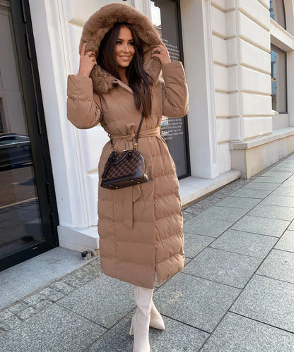 Woman wearing a long brown puffer coat on a city street.