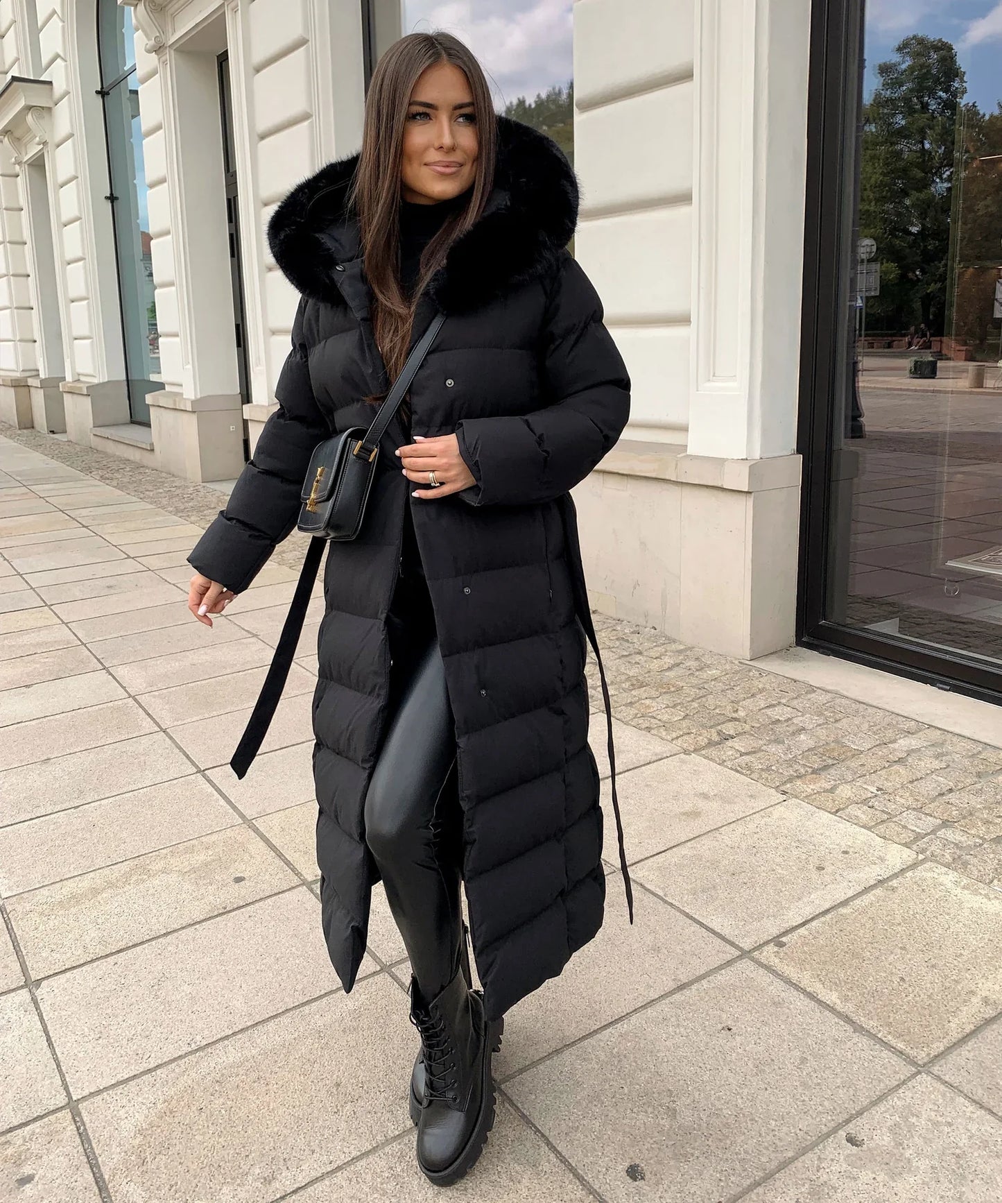 Woman wearing a long black puffer coat in an urban setting