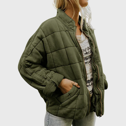 Person wearing a green quilted jacket on a plain background