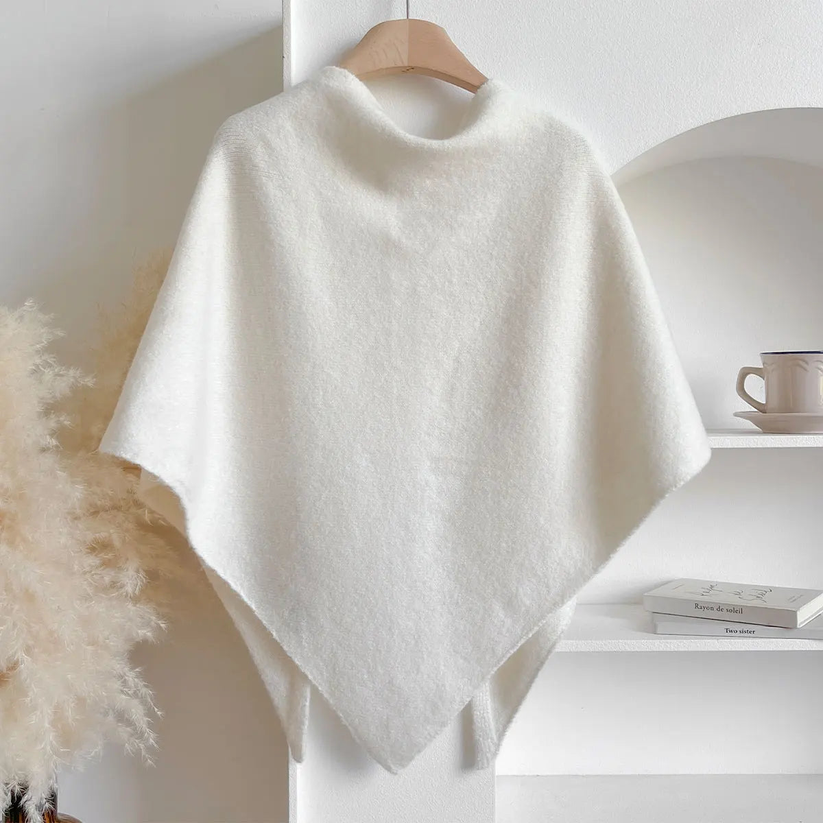 White poncho on a wooden hanger against a neutral background