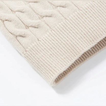 Close-up of a beige knitted sweater with cable pattern on a white background