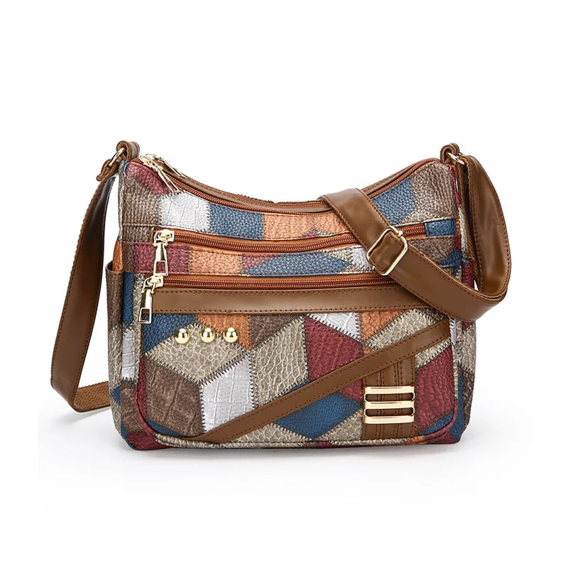 Multicolored patchwork handbag with brown leather straps on a white background