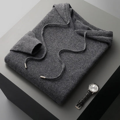 Folded gray sweater on a gray surface with a watch beside it