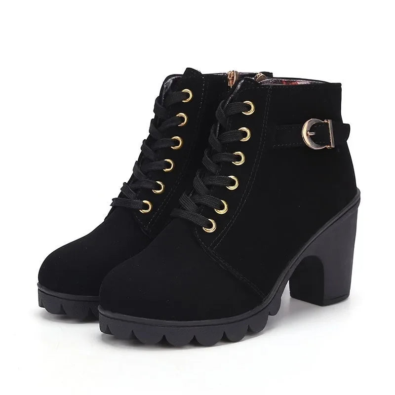 Black suede ankle boots with gold laces on a white background