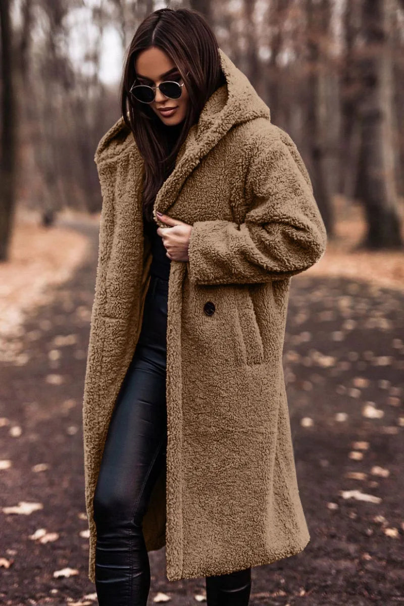 Woman wearing a long brown coat in a forest setting