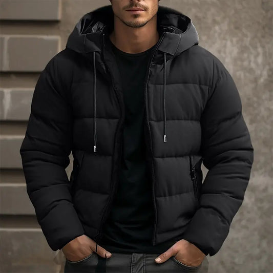 Man wearing a black puffer jacket against a neutral background