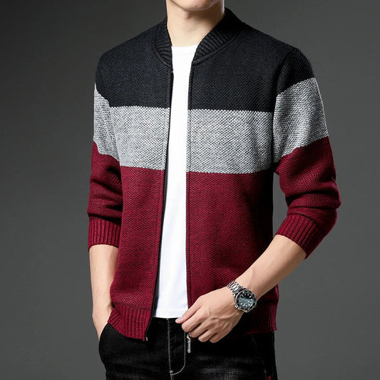 Person wearing a black, gray, and red striped sweater on a gray background