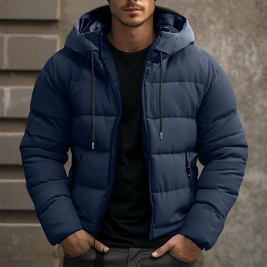 Man wearing a blue puffer jacket standing against a neutral background