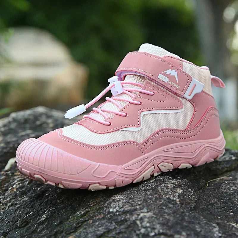 Pink and white hiking boot on a stone surface with a blurred green background