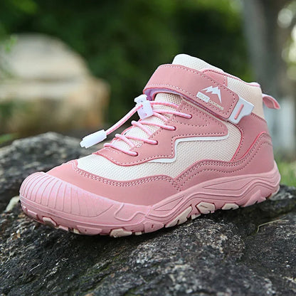 Pink and white hiking boot on a stone surface with a blurred green background