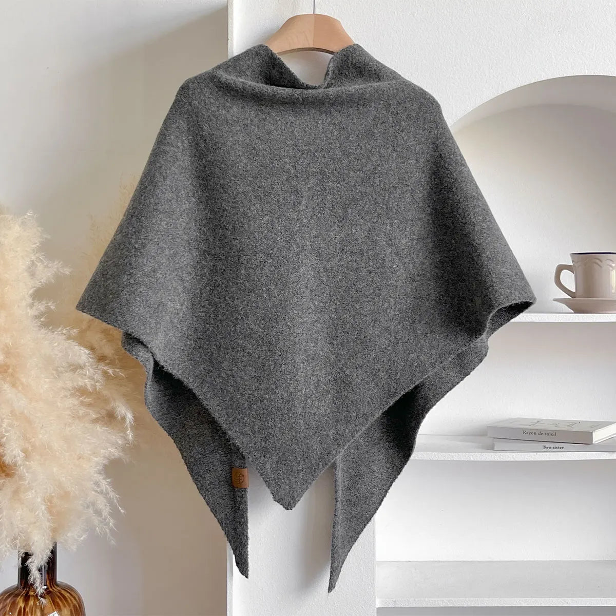 Gray poncho on a hanger against a neutral background