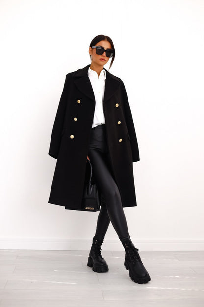 Person wearing a black coat with gold buttons on a white background
