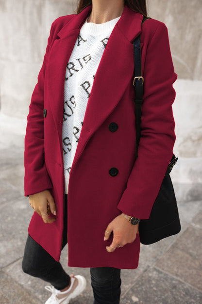 Person wearing a red coat over a white graphic t-shirt, standing on a stone pavement.