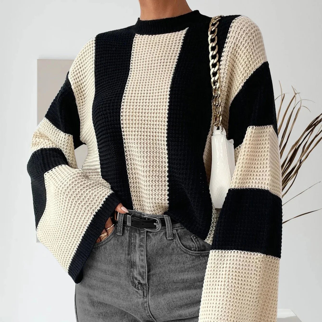 Person wearing a black and beige striped sweater with a white background