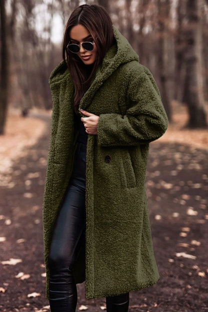 Woman wearing a green coat in a forest setting