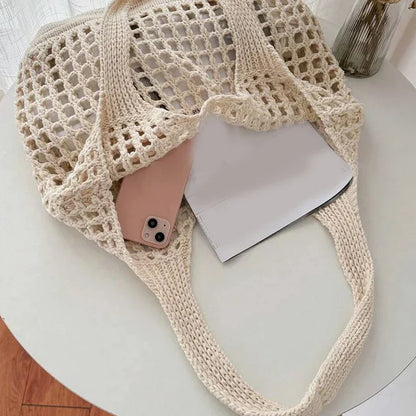 Beige knitted bag with a phone and paper on a white surface