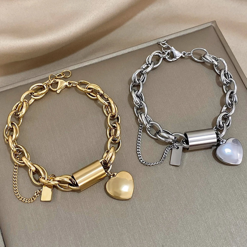 Gold and silver chain bracelets with heart charms on a neutral background