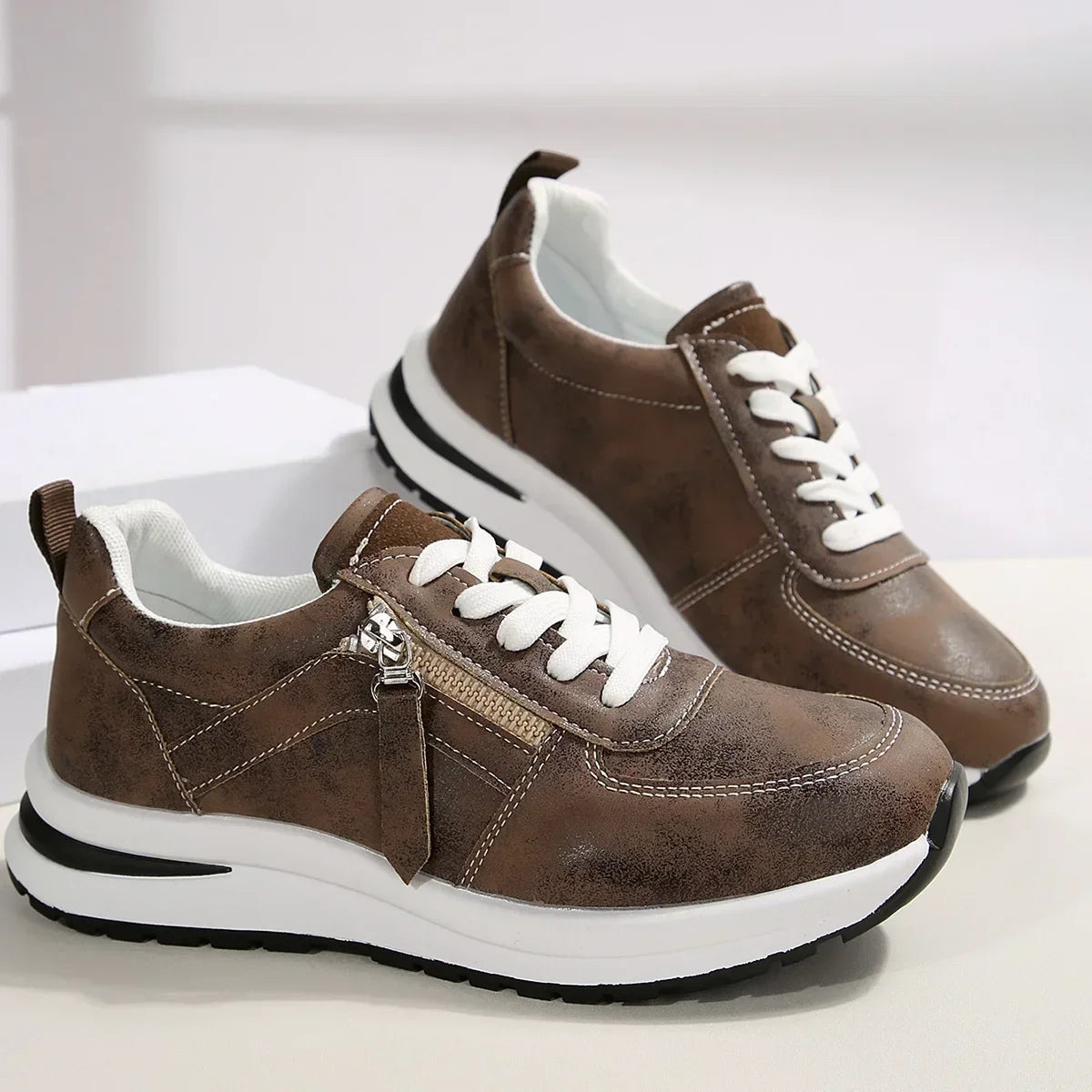 Brown sneakers with white laces and soles on a light background
