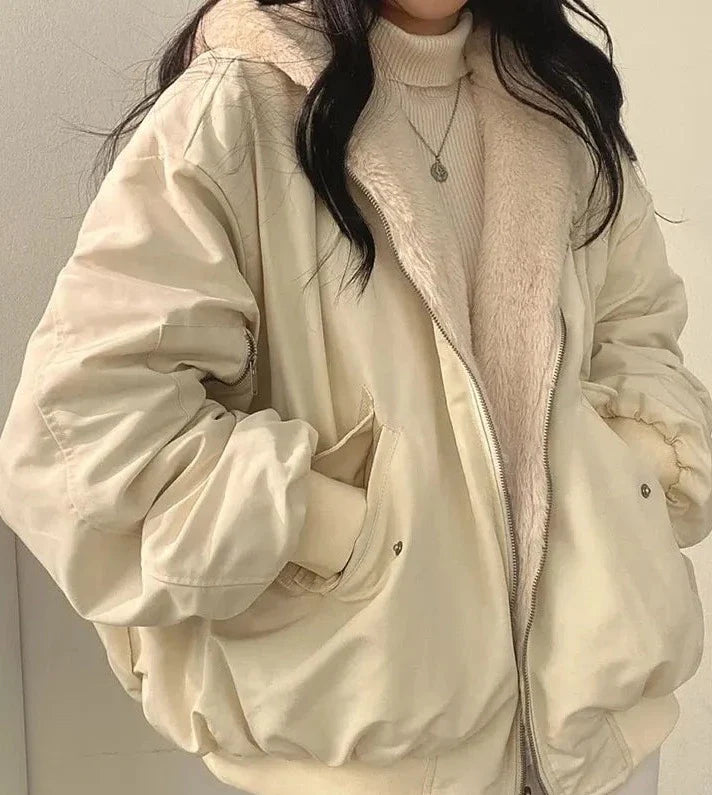 Person wearing a beige puffer jacket over a light pink sweater against a neutral background