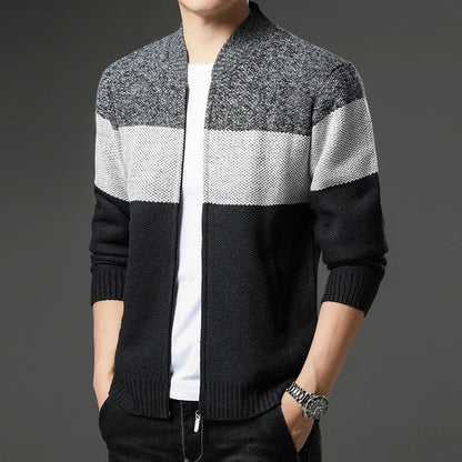 Person wearing a black, gray, and white striped sweater on a dark background