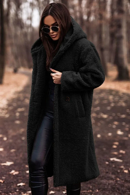 Woman wearing a dark coat and sunglasses in a forest setting