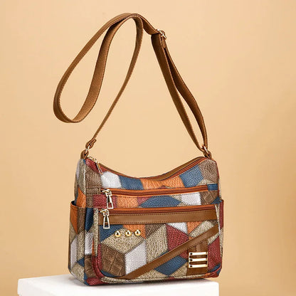 Multicolored patchwork handbag with brown strap on beige background