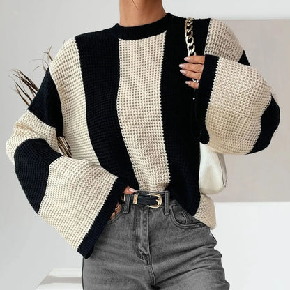 Person wearing a black and white striped sweater with a plain background