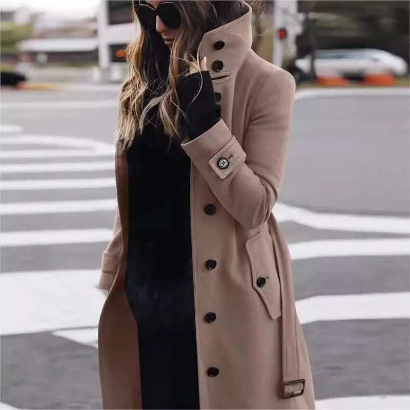 Person wearing a beige trench coat with black buttons on a city street.
