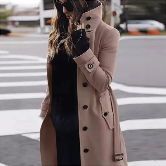 Person wearing a beige trench coat with black buttons on a city street.