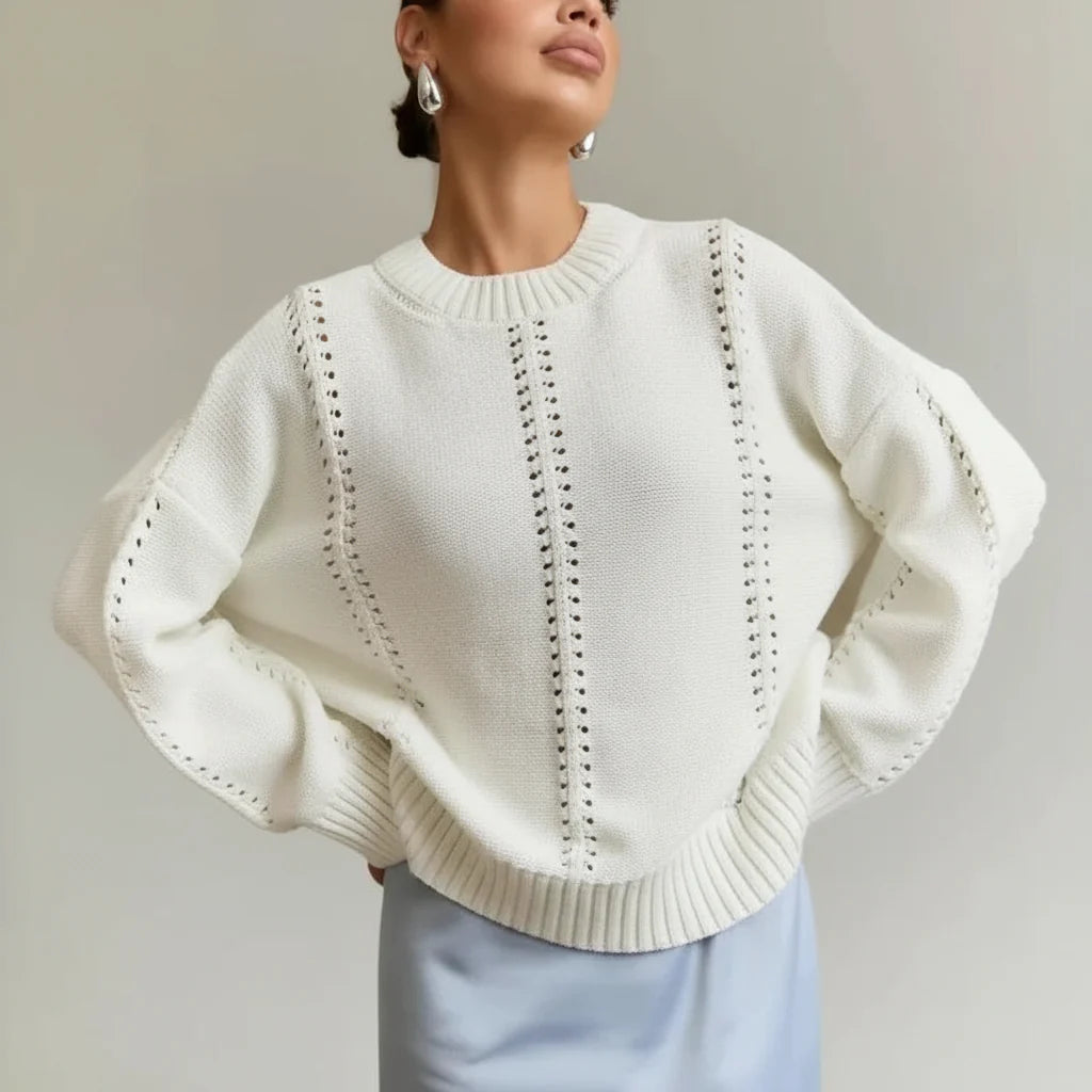 Woman wearing a white knit sweater with a textured pattern against a plain background