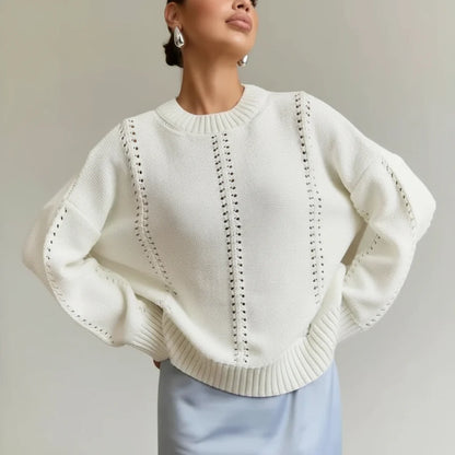 Woman wearing a white knit sweater with a textured pattern against a plain background