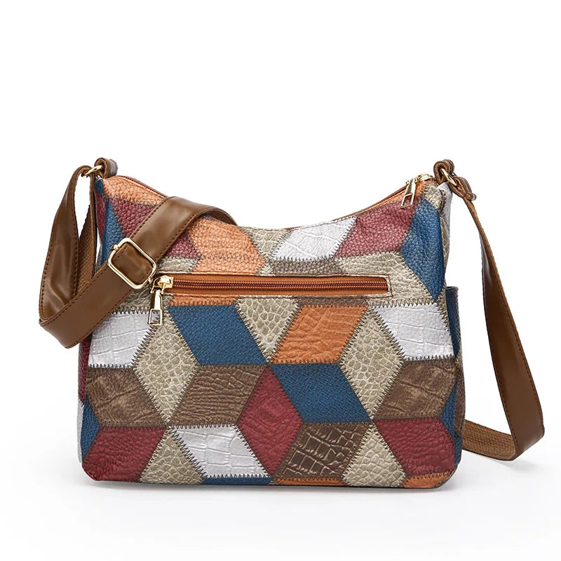 Multicolored patchwork handbag with brown leather straps on a white background