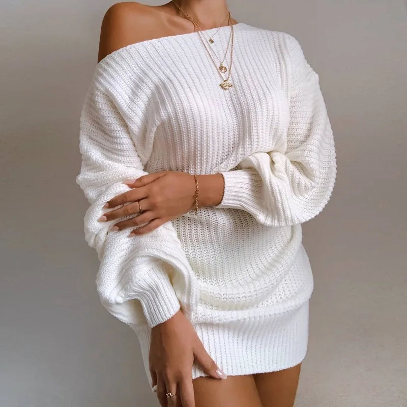 White knitted off-shoulder sweater worn by a person on a plain background