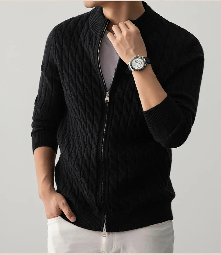 Person wearing a black cable knit sweater with a zipper on a light gray background