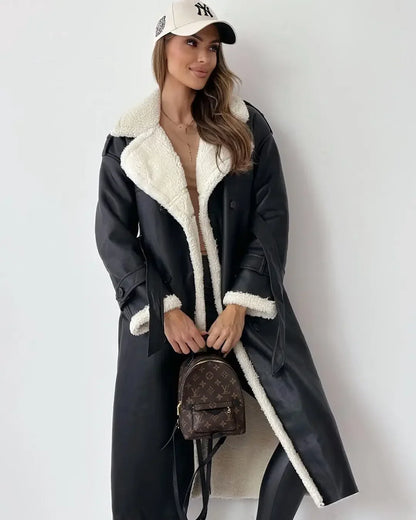 Woman wearing a black coat with white fur lining, holding a brown handbag against a white background