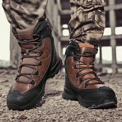 Brown hiking boots with black soles worn by a person in camouflage pants on a rocky ground.